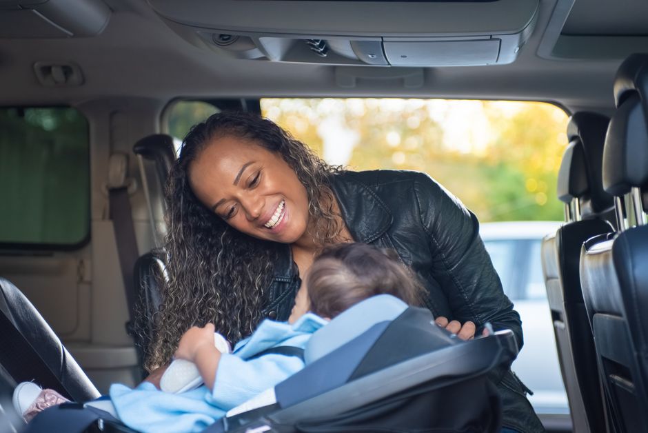 Mother smiling at baby in car seat safely