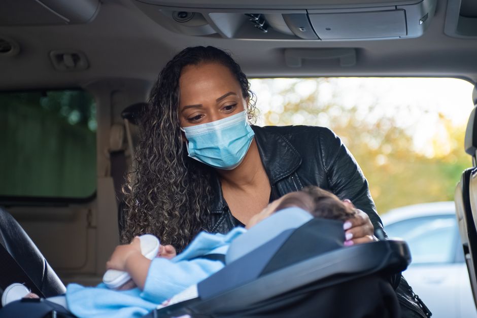 Mother buckling baby into car seat properly