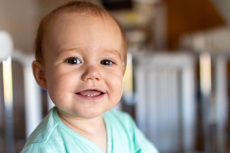 A smiling baby in a bright indoor room playing safely