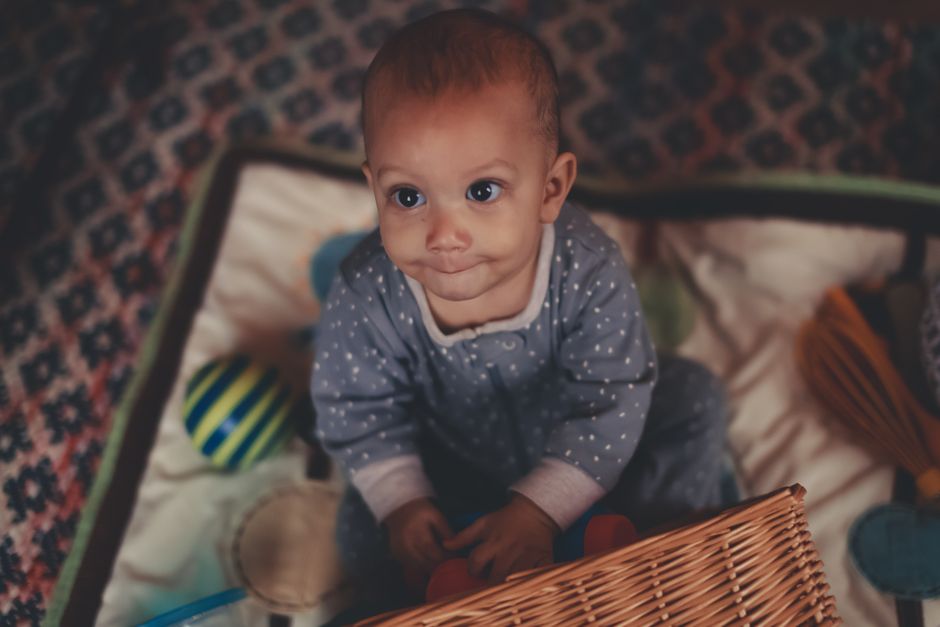 Cute baby in pajamas playing with toys on a soft floor mat indoors