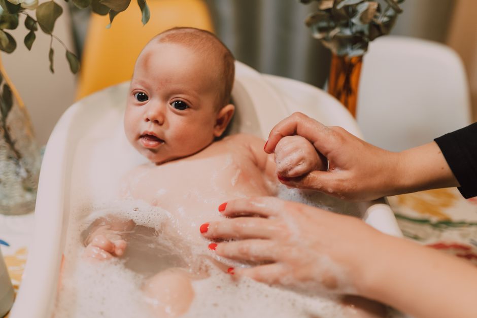 Young child playfully looking down while sitting in a bathtub