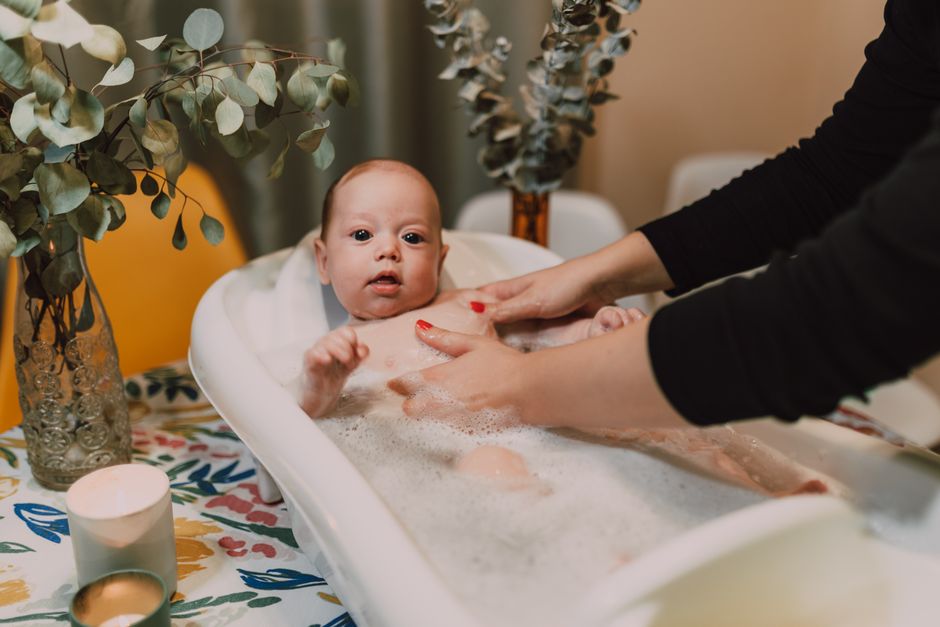 A serene scene of a baby enjoying a bubble bath indoors surrounded by soothing elements