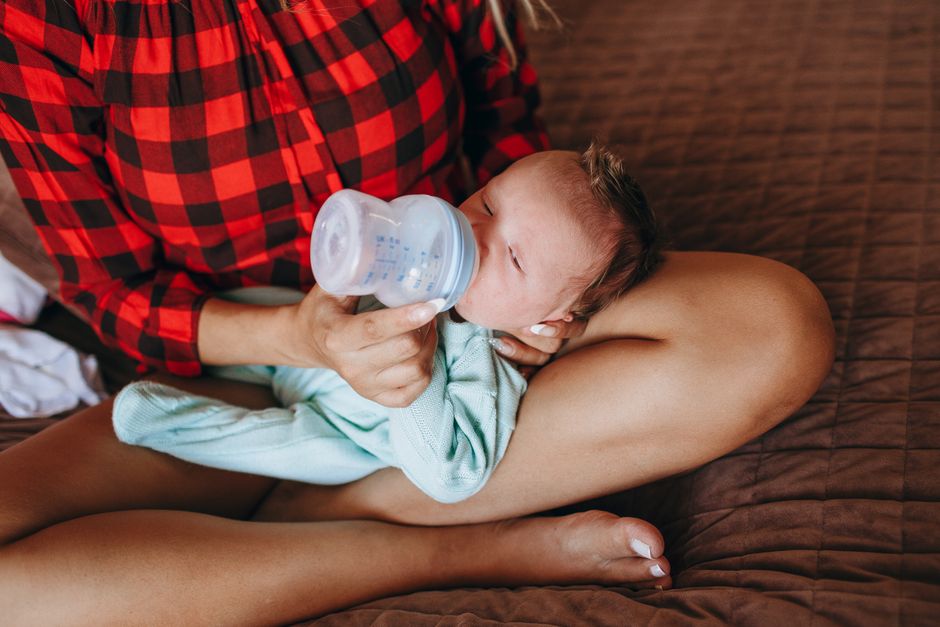 Close up of mother gently comforting baby on bed after feeding