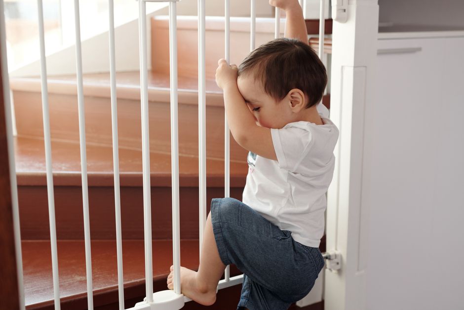 A curious toddler exploring near a safety gate indoors