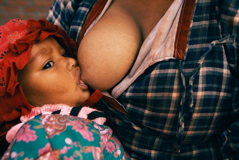 Close-up of a mother gently feeding and holding her newborn baby in the evening