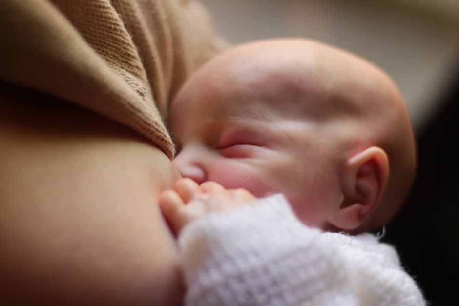 A mother breastfeeding her newborn baby in soft evening lighting