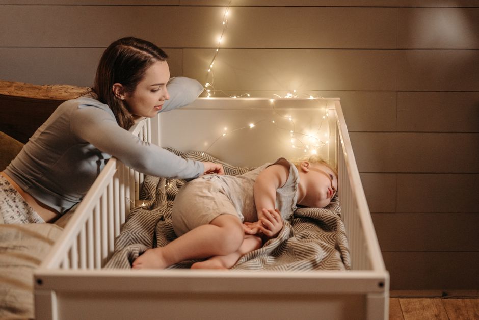 Mother gently checking on baby in peaceful nighttime nursery