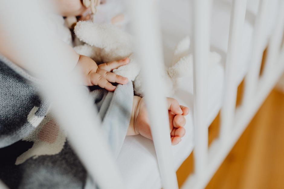 Adorable baby sleeping peacefully in a crib next to a soft blanket