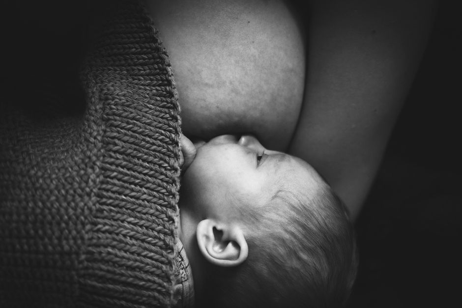 Mother holding newborn close during breastfeeding session