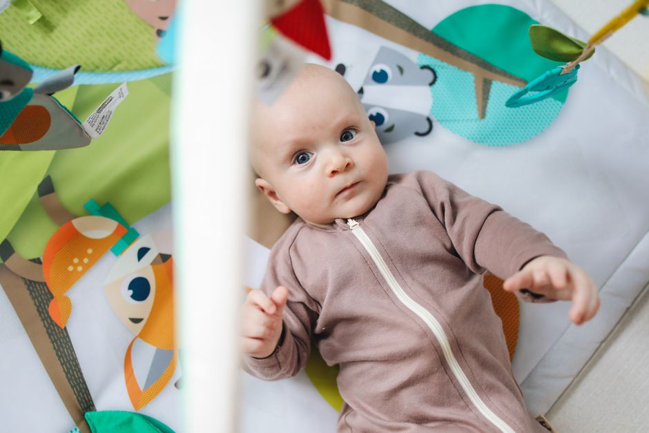 A baby playing safely on an unrestricted floor play mat indoors