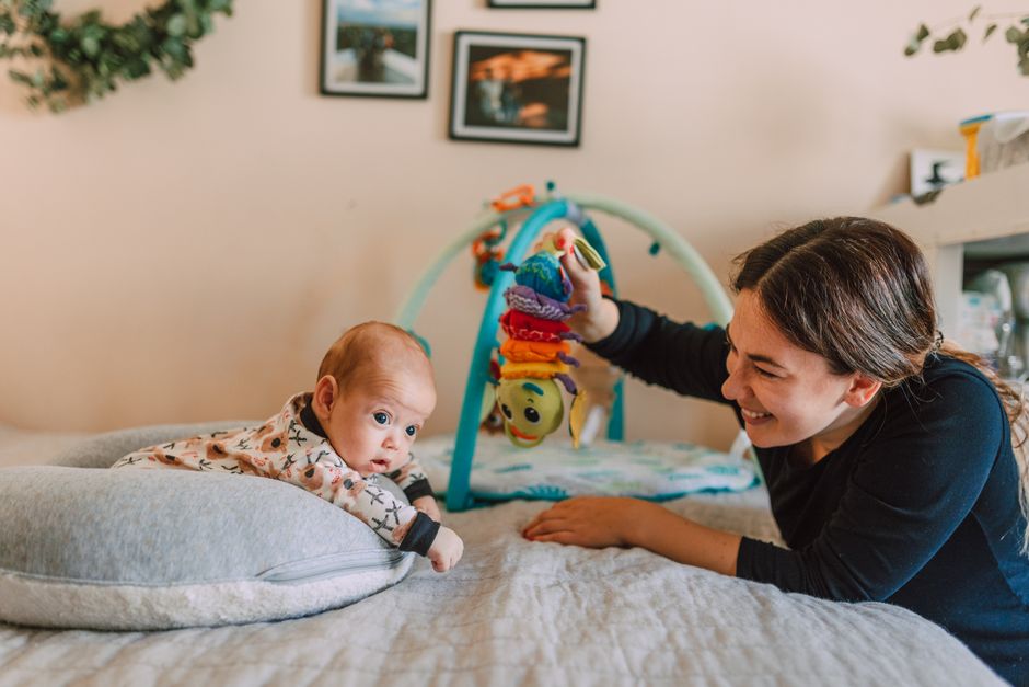 Smiling mother playing with baby on bedd