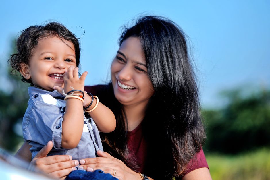 A smiling mother lovingly looking at her young child outdoors