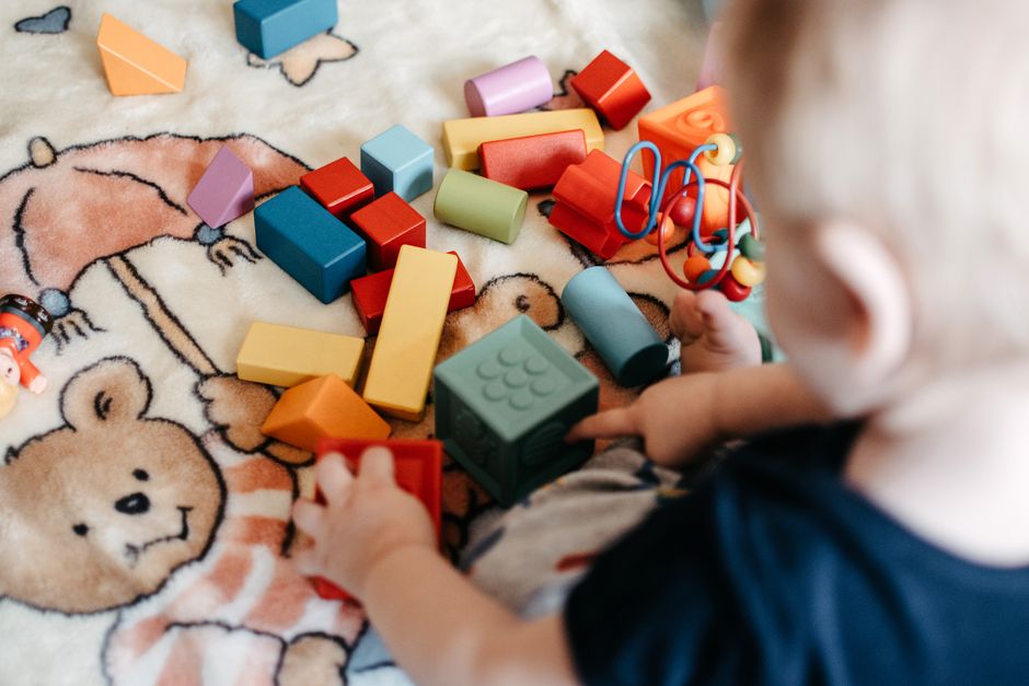 Toddler joyfully playing with a variety of colorful building blocks