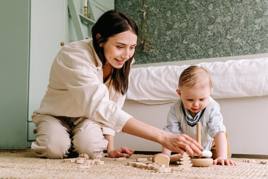 Mother and baby bonding over wooden toys on the floor