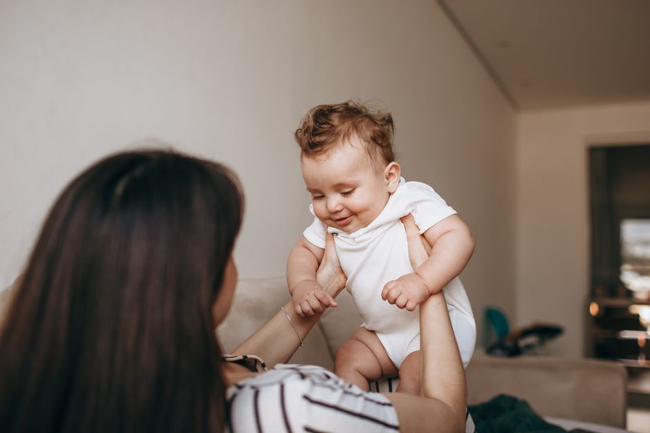 Mother joyfully smiling and connecting face-to-face with her responsive baby
