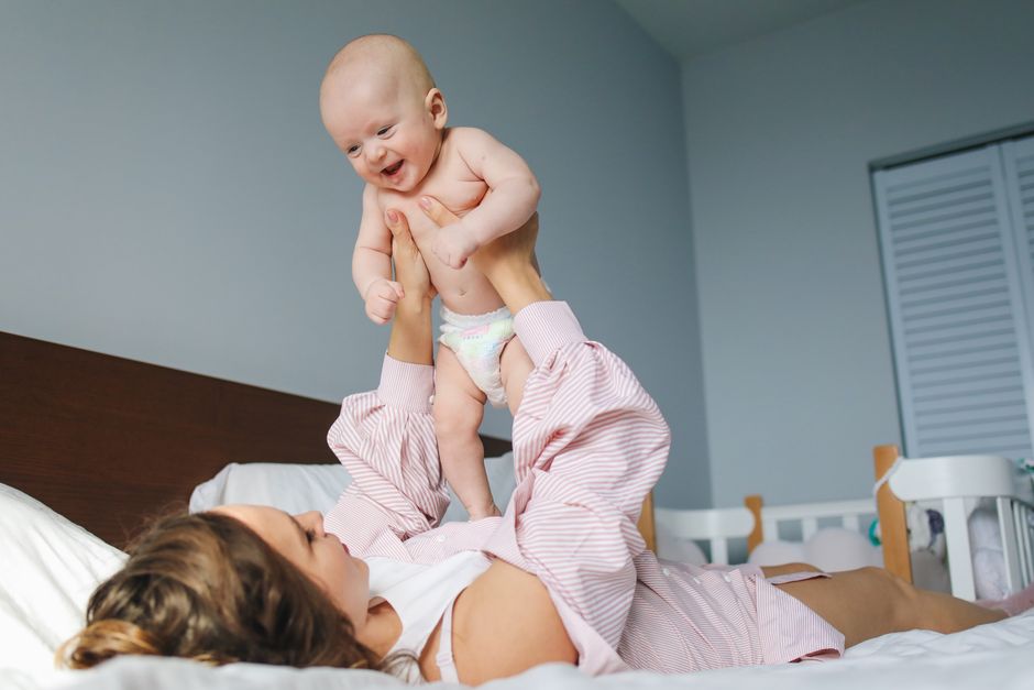 Mother holding happy baby tenderly in bedroom