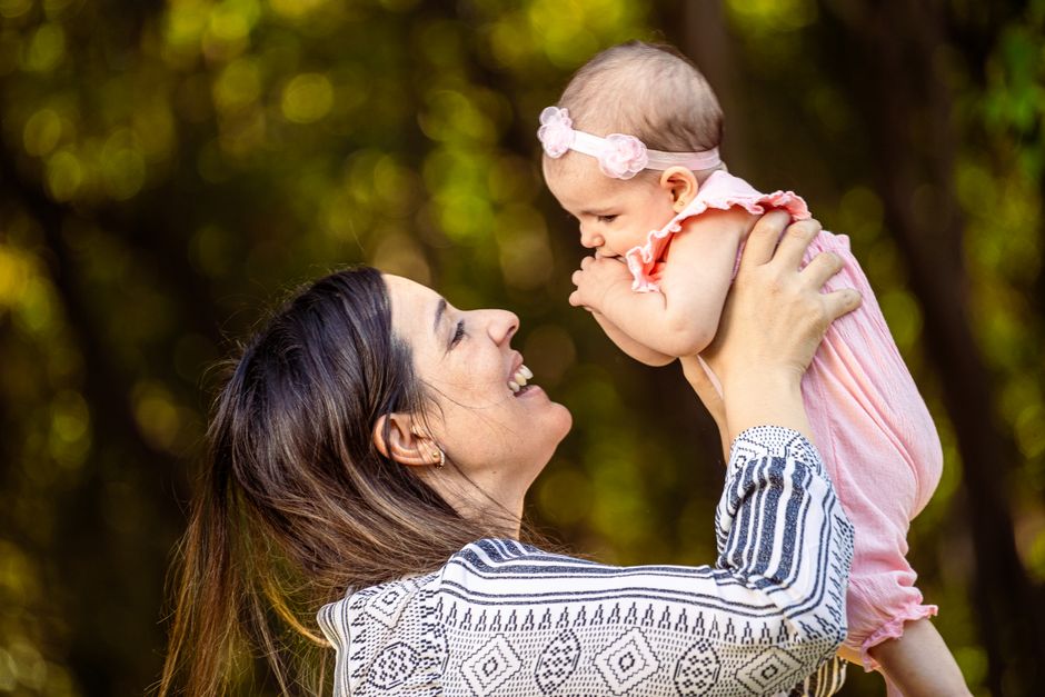 Mother holding smiling baby in the air celebrating milestone