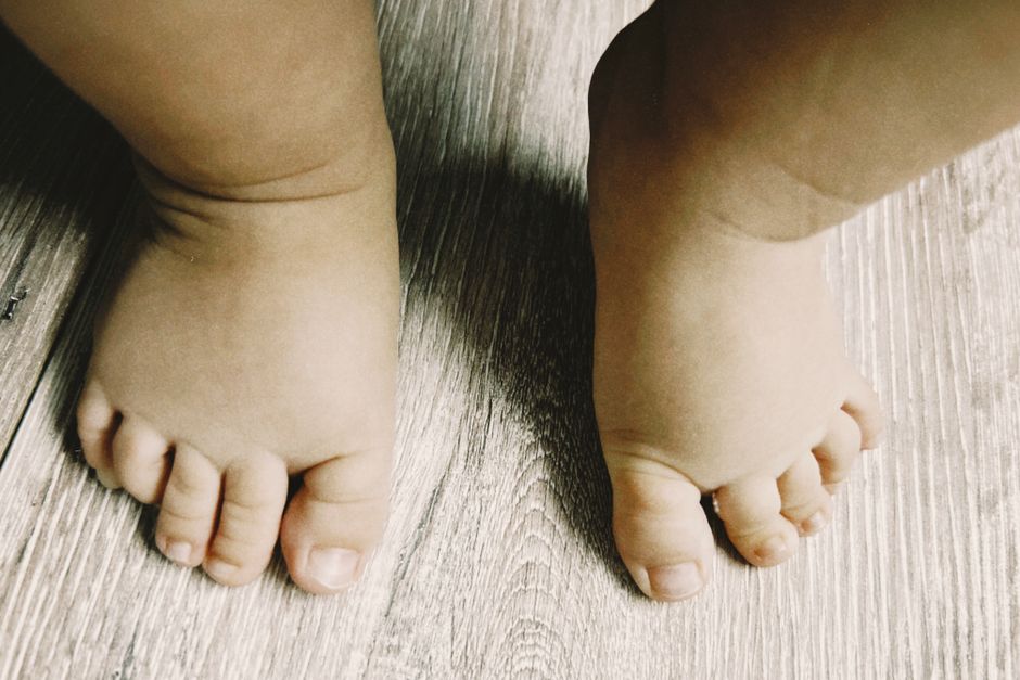 Close-up of baby feet standing on a wooden floor, capturing innocence