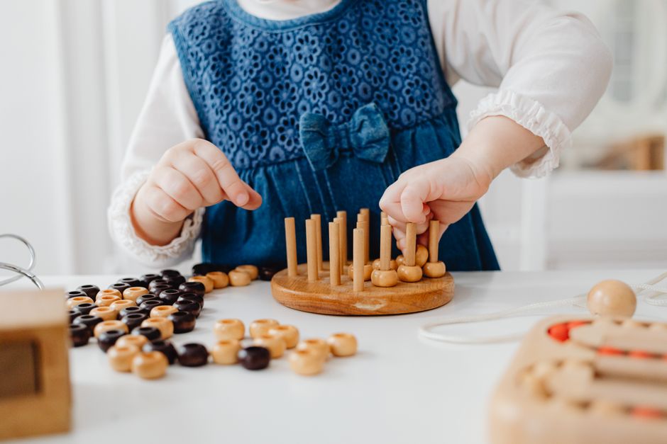 A child interacts with a wooden sorting toy, developing fine motor skills