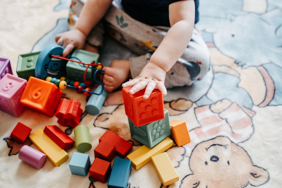 Toddler engaging with vibrant toy blocks on a patterned rug