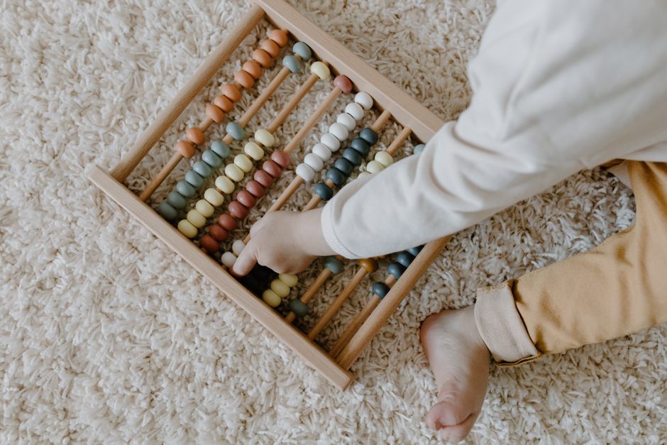 A young child interacts with a colorful wooden abacus