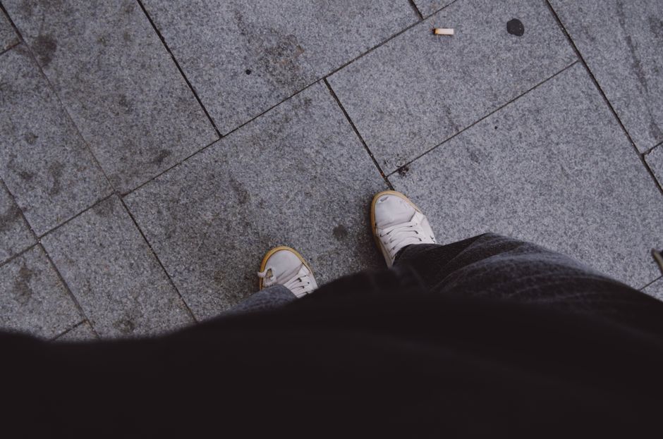 Overhead view of footwear and footsteps on street