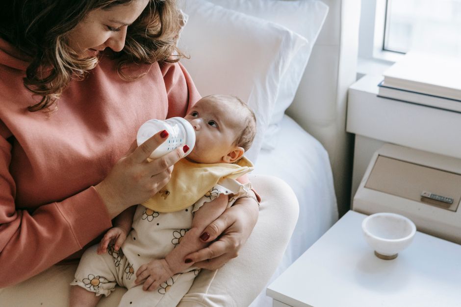 Mother holding and feeding baby close up