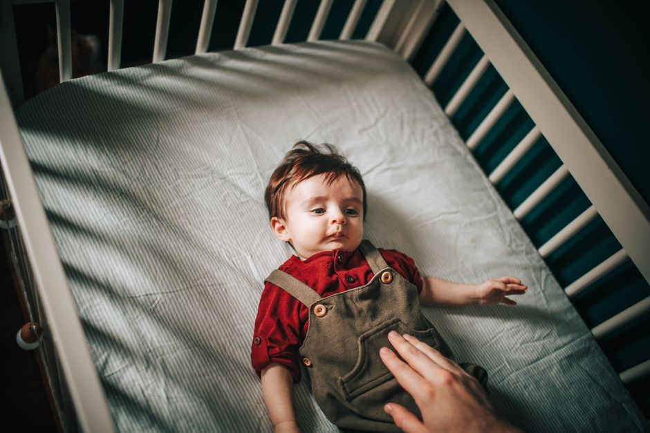 Parent soothing baby in the crib