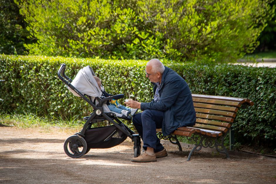 A family safely strolling with a baby carriage in the shaded park
