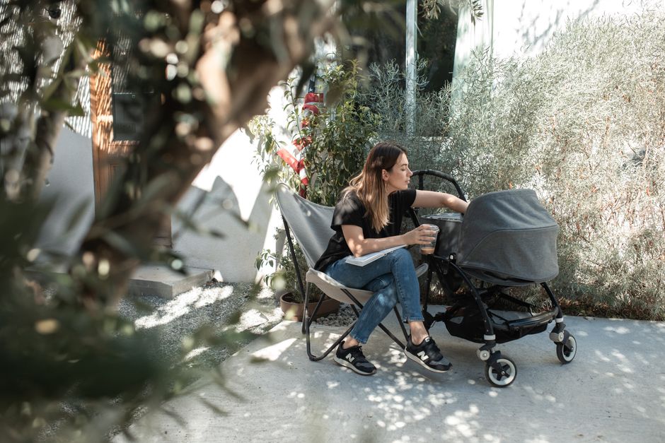 Mother with stroller enjoying a sunny park day under shade canopy