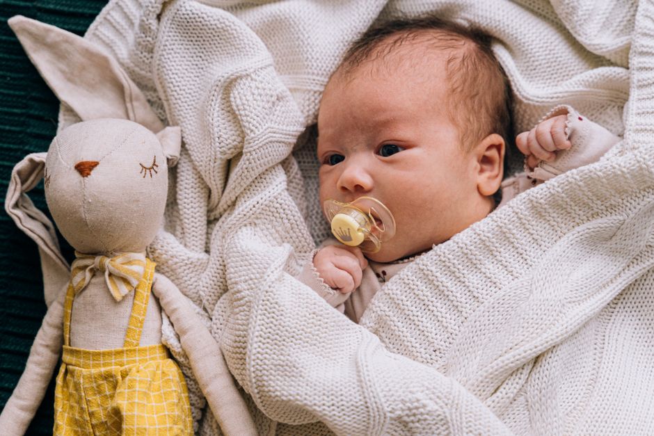 Adorable newborn wrapped in cozy blanket with a pacifier