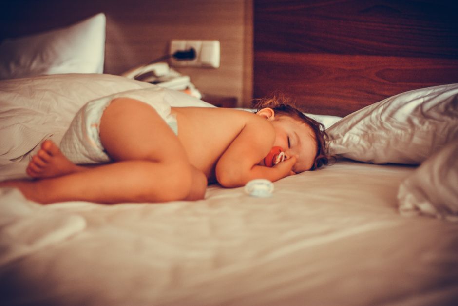 A baby resting comfortably on a soft bed in natural morning light