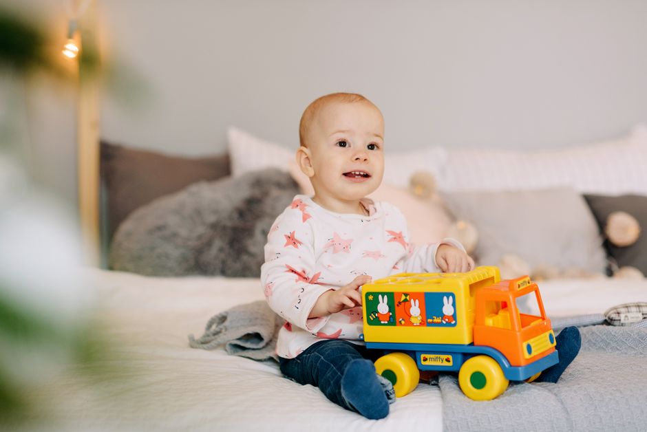Baby safely sitting on rug playing with large wooden blocks