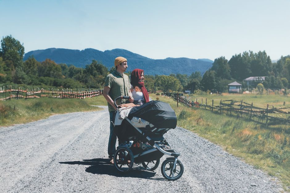 Family enjoying outdoor walk with baby carriage under open shaded trees