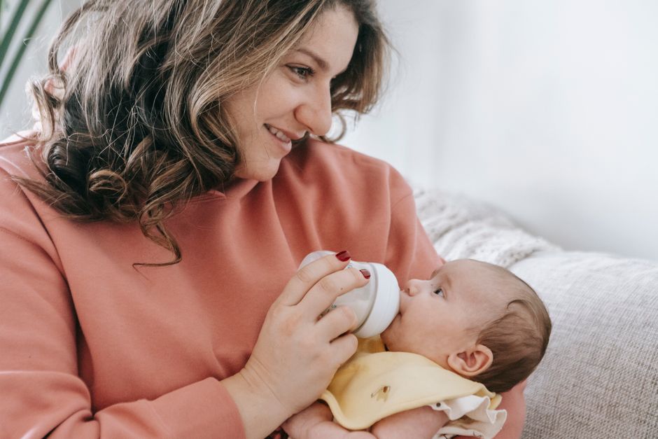Loving mother gently bottle feeding her infant baby in a peaceful nursery setting
