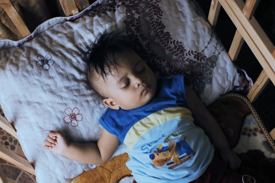 A toddler sleeping soundly in a crib, capturing childlike innocence and serenity