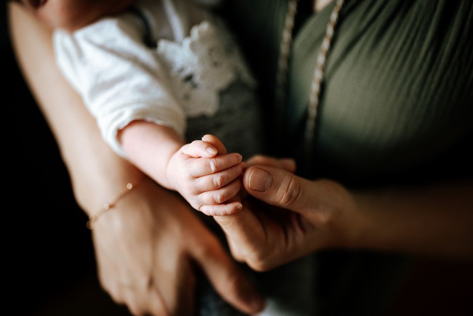 Close-up of mother holding baby hand tenderly