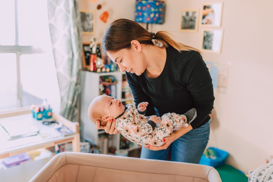 A mother lovingly holds her newborn baby in a cozy nursery, symbolizing motherhood and togetherness