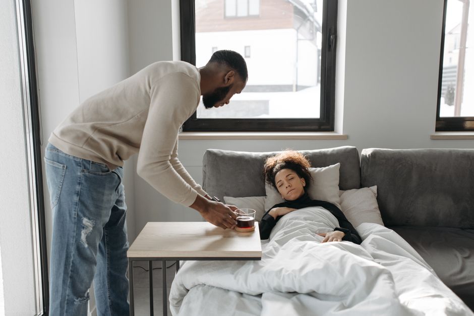 A supportive partner bringing tea and care during recovery