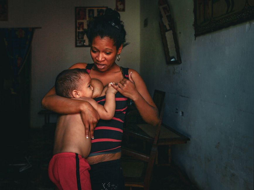Mother tenderly breastfeeding her child in indoor setting, capturing a touching family moment