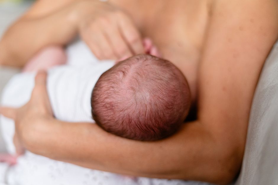 A mother tenderly holding and protecting her infant baby in a warm room