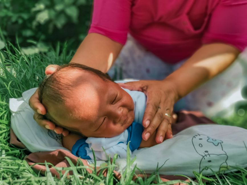 Mother tenderly watching her resting baby outdoors