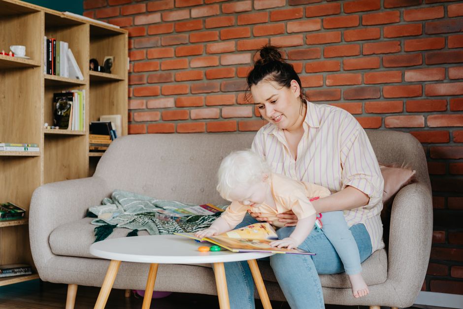 A cozy, sunlit living room with a woman reading a book on the sofa