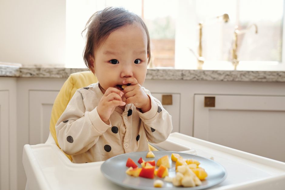 Toddler exploring finger food textures in high chair