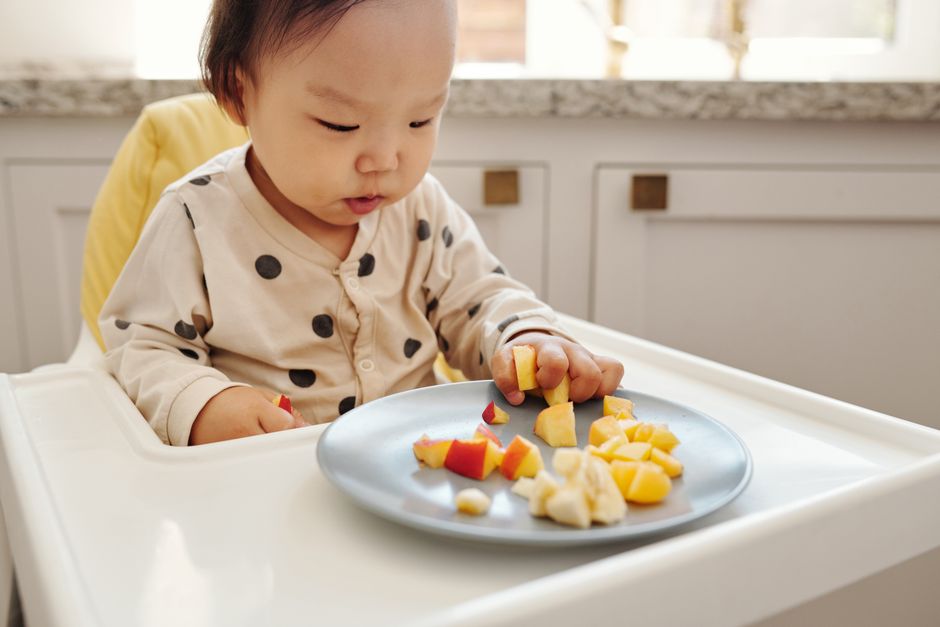 Baby happily tasting real foods in a modern kitchen