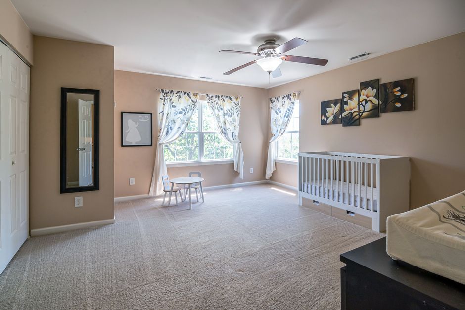 Spacious and pristine nursery room with crib and soft carpet