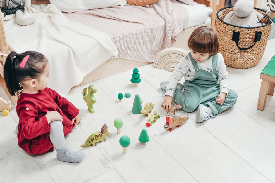Two young children playing peacefully with wooden toys
