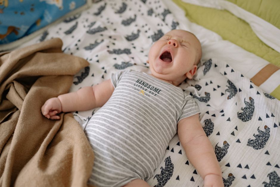 A baby yawning cozily in their nursery crib