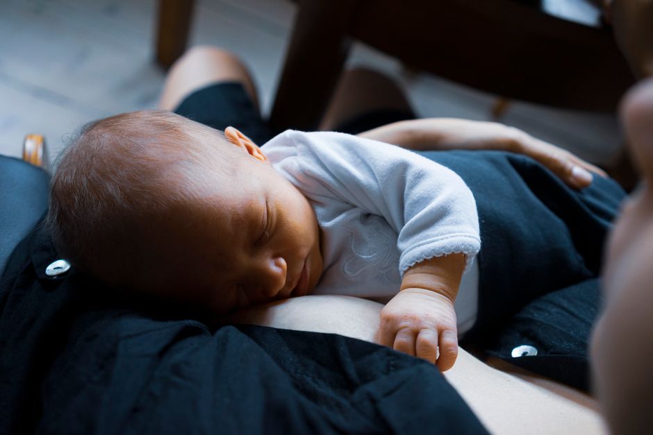 Mother pondering peacefully near window holding newborn