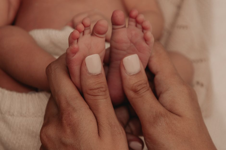Tender close-up of mother gently holding her newborn baby's feet with loving hands